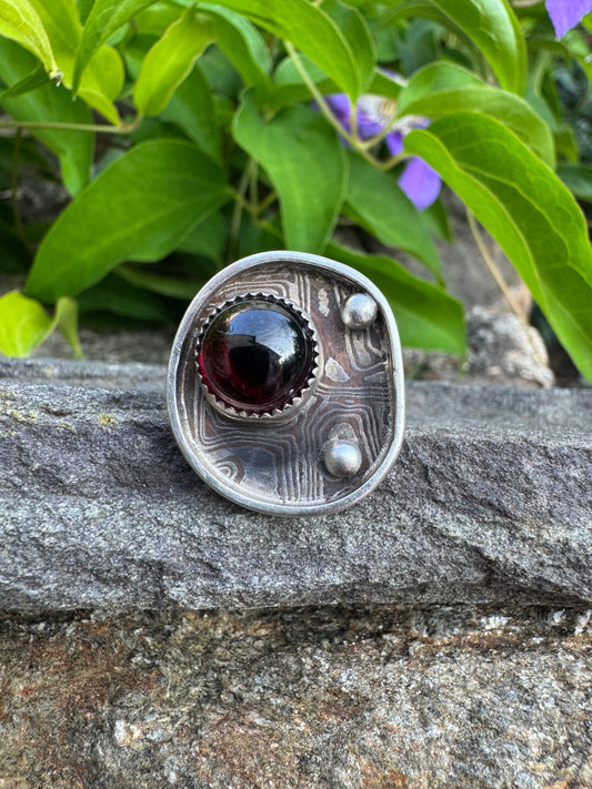 Handmade sterling silver garnet ring with Mokume Gane band, front view