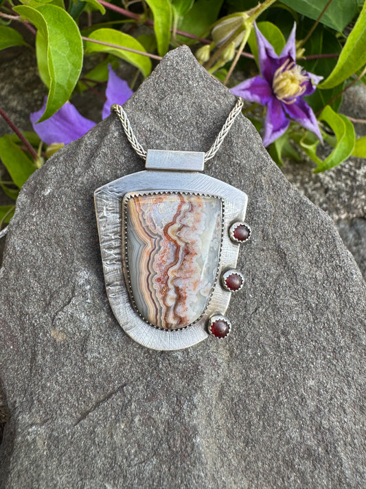 Handmade sterling silver shield-cut crazy lace agate pendant with garnets, front view